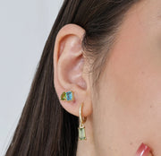 Gold hoop earrings with dangling green amethyst baguette-cut stone, finished in 18K yellow gold plating.